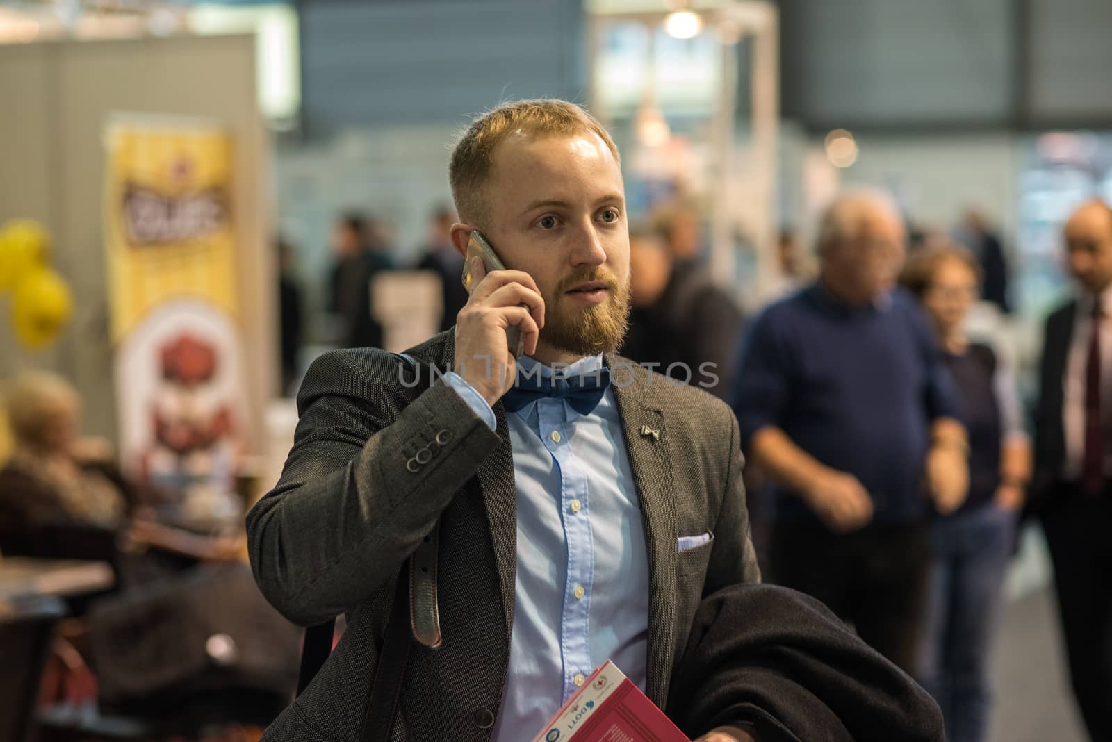 A man is walking while speaking on the phone at the convention trade center in Brno taking some time to have a coffee. BVV Brno Exhibition center. Czech Republic