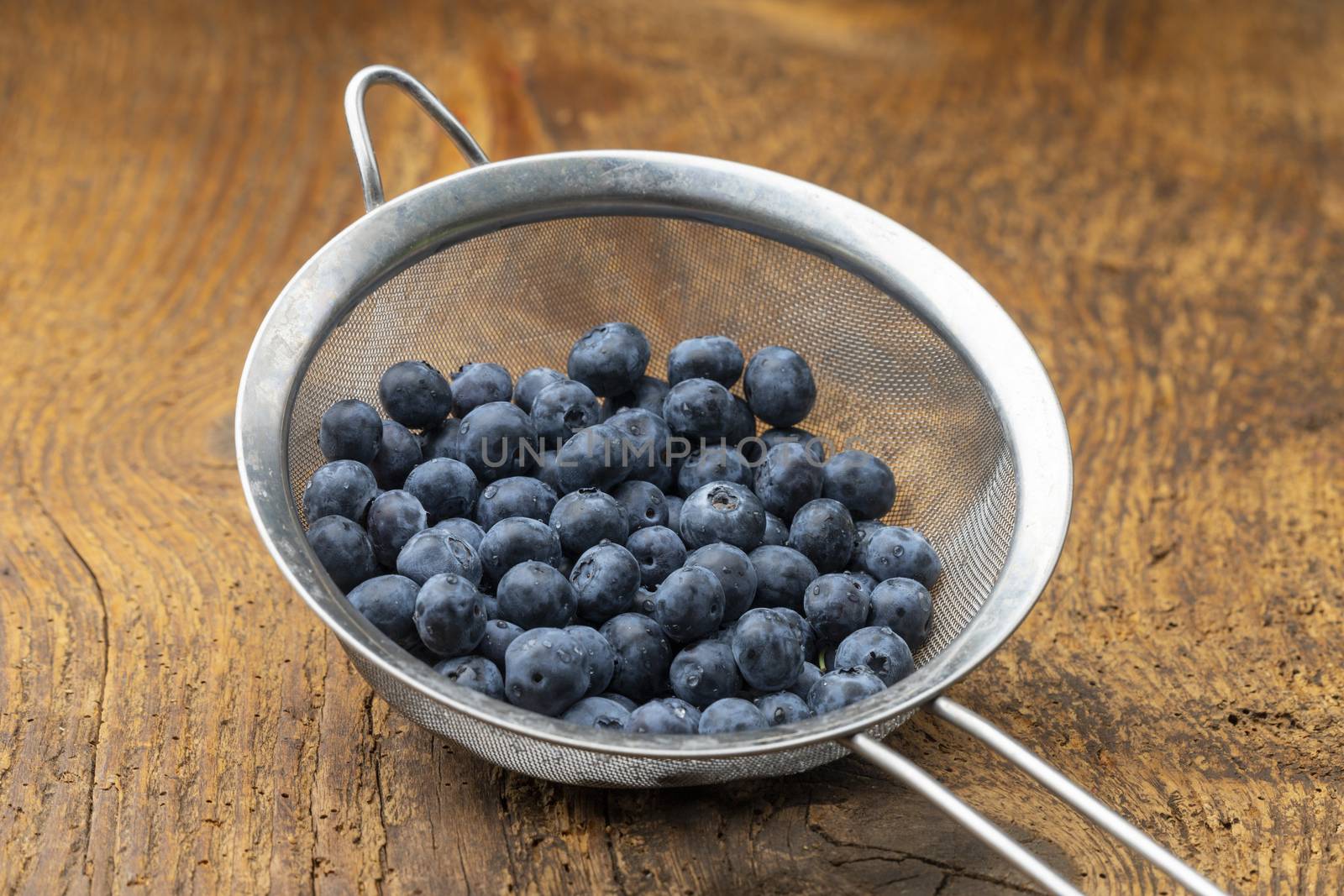 blue berries in a sieve on wood