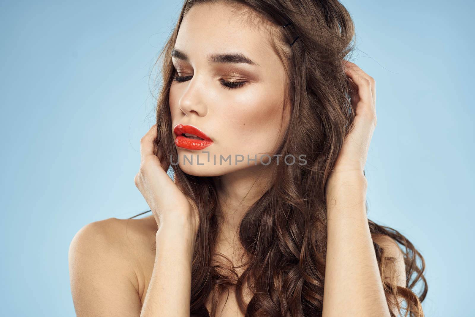 Elegant brunette fashionable hairstyle bright makeup naked shoulders close-up blue background. High quality photo