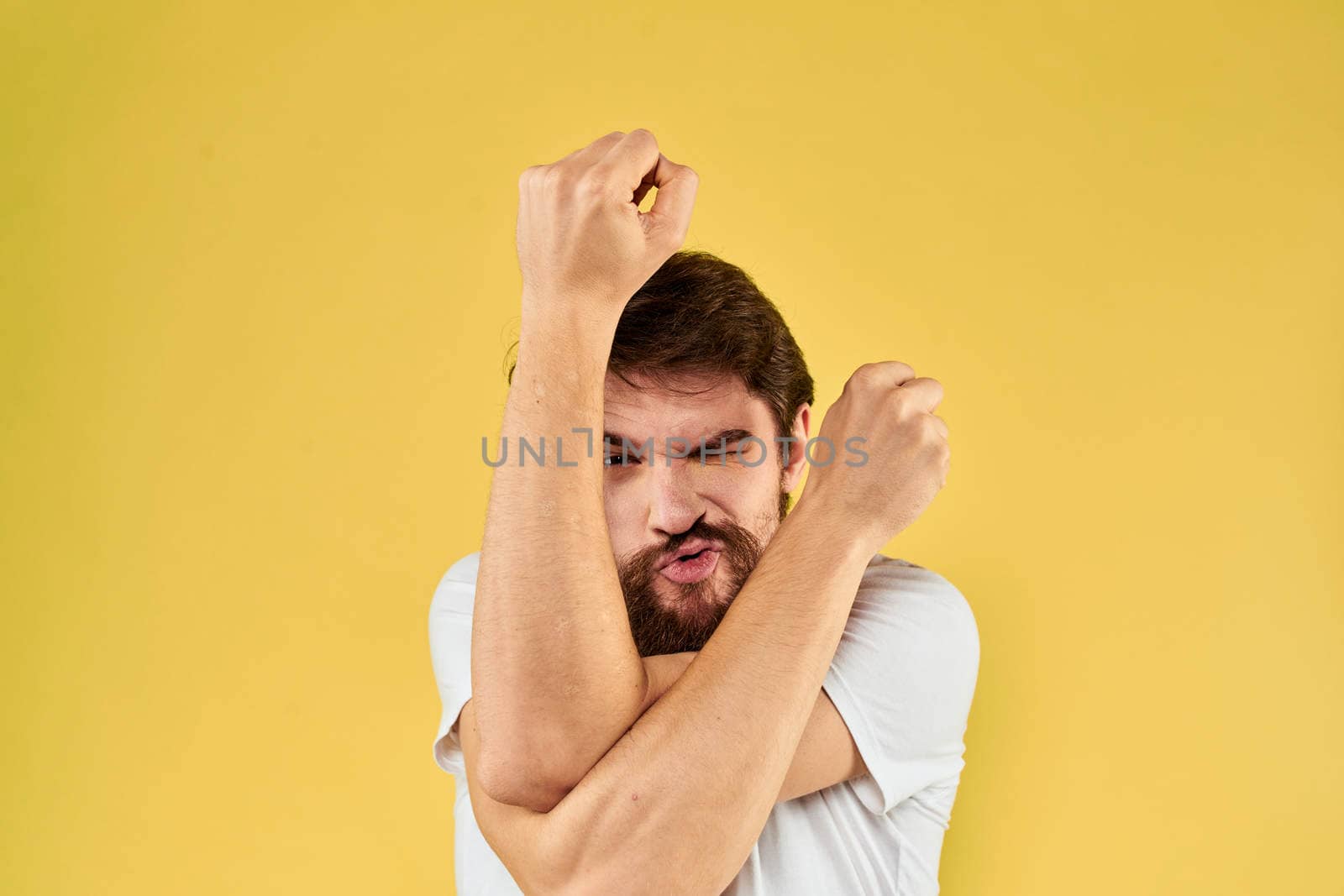 A man in a white t-shirt gestures with his hands lifestyle cropped view yellow background more fun by SHOTPRIME