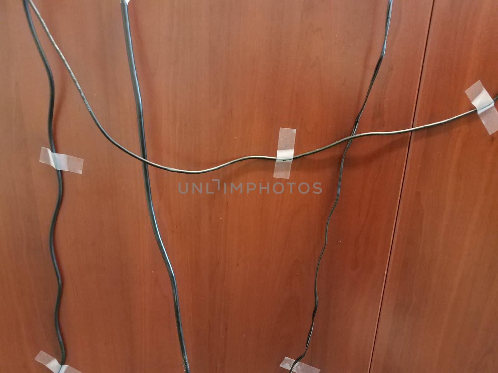 computer wires or cables taped to a brown wood desk