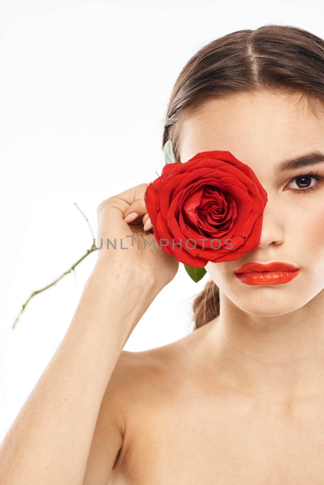 charming brunette girl with makeup on her face and a red rose in her hand. High quality photo