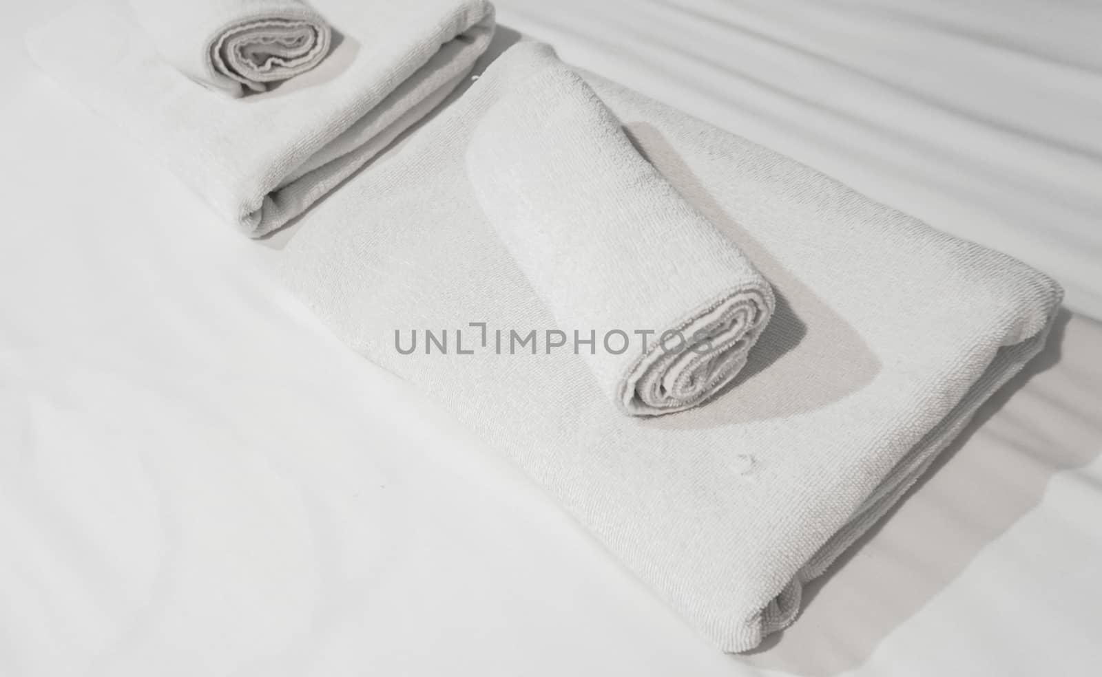 Pile of White Towels on bedsheet by Urvashi-A