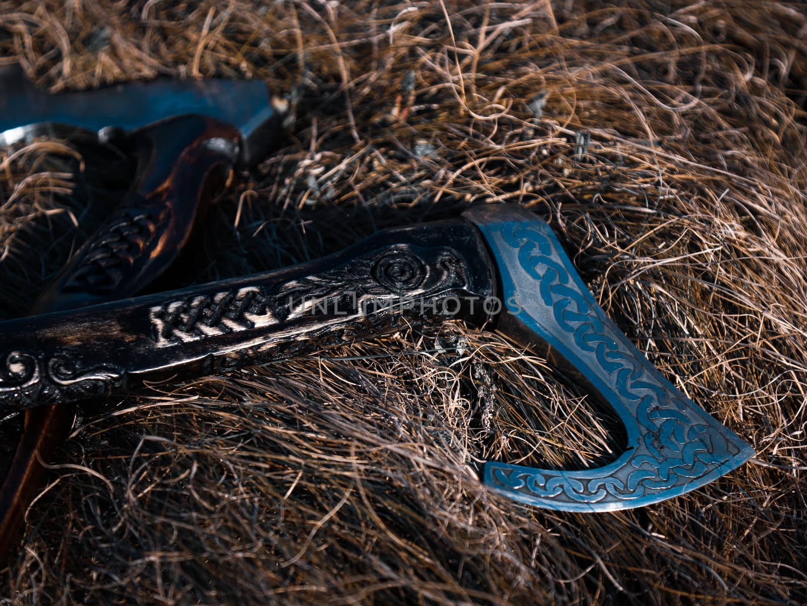 Close up look at the ancient Scandinavian vikings axe at the summer sunset on the deep grass