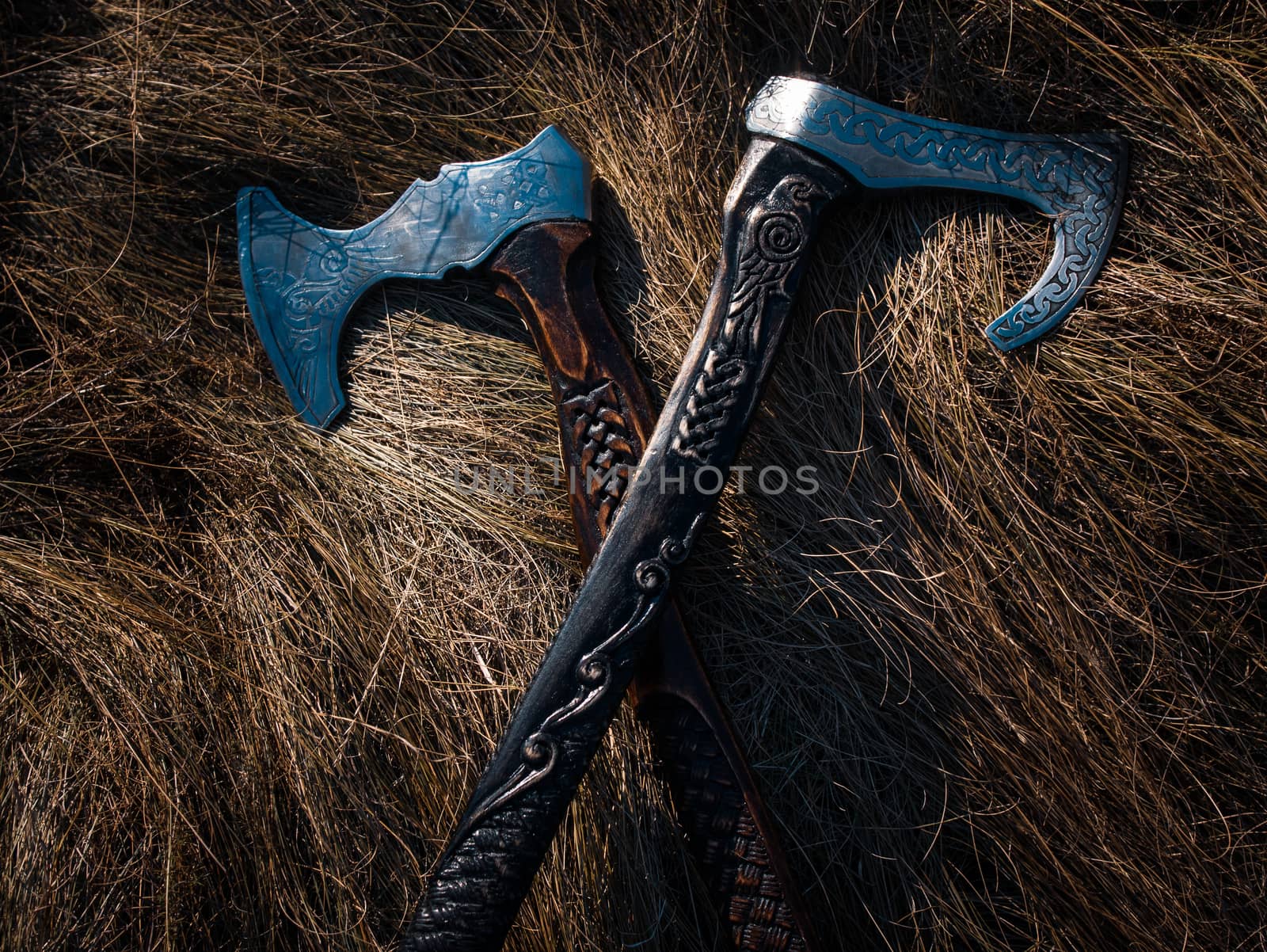 Close up look at the ancient Scandinavian vikings axe at the summer sunset on the grass by VIIIPhoto