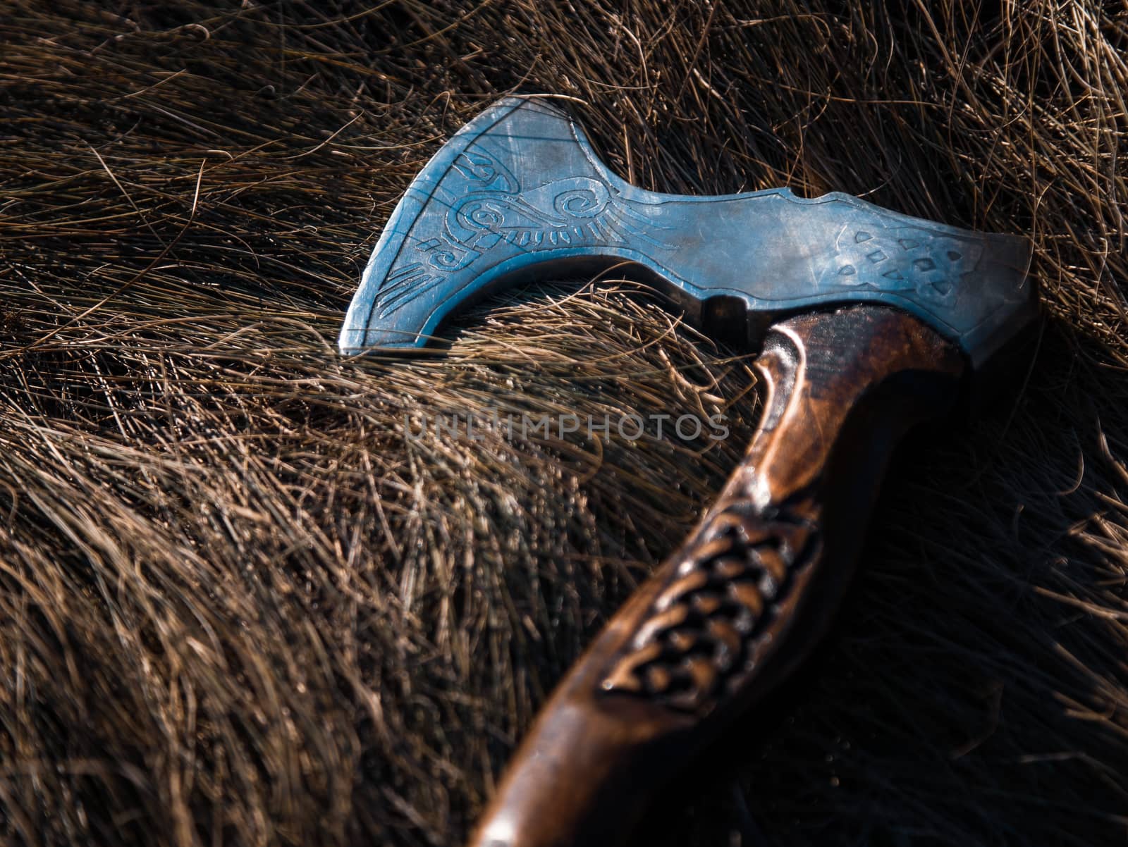Close up look at the ancient Scandinavian vikings axe at the summer sunset on the deep grass