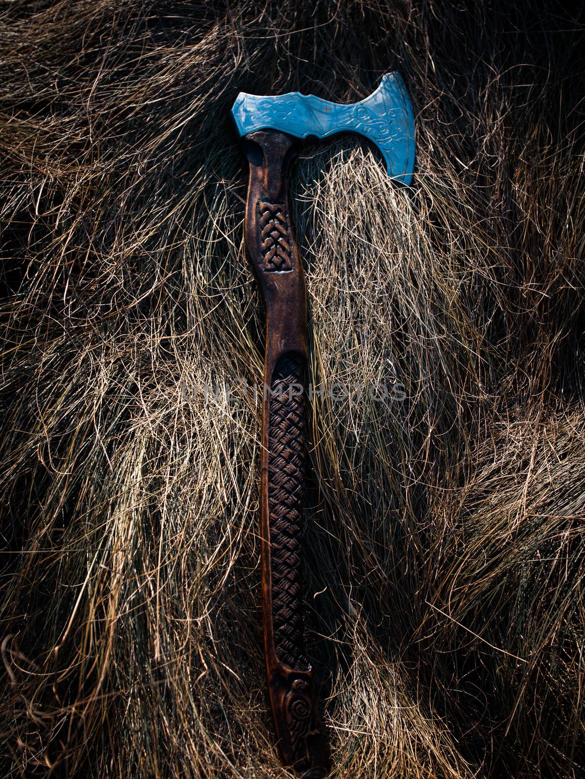 Close up look at the ancient Scandinavian vikings axe at the summer sunset on the deep grass