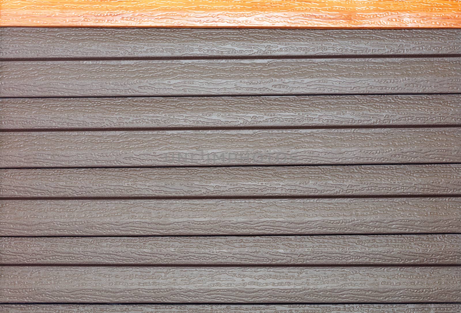 Brown vinyl siding with imitation wood grain. Vinyl texture and siding background in exterior wall surface.