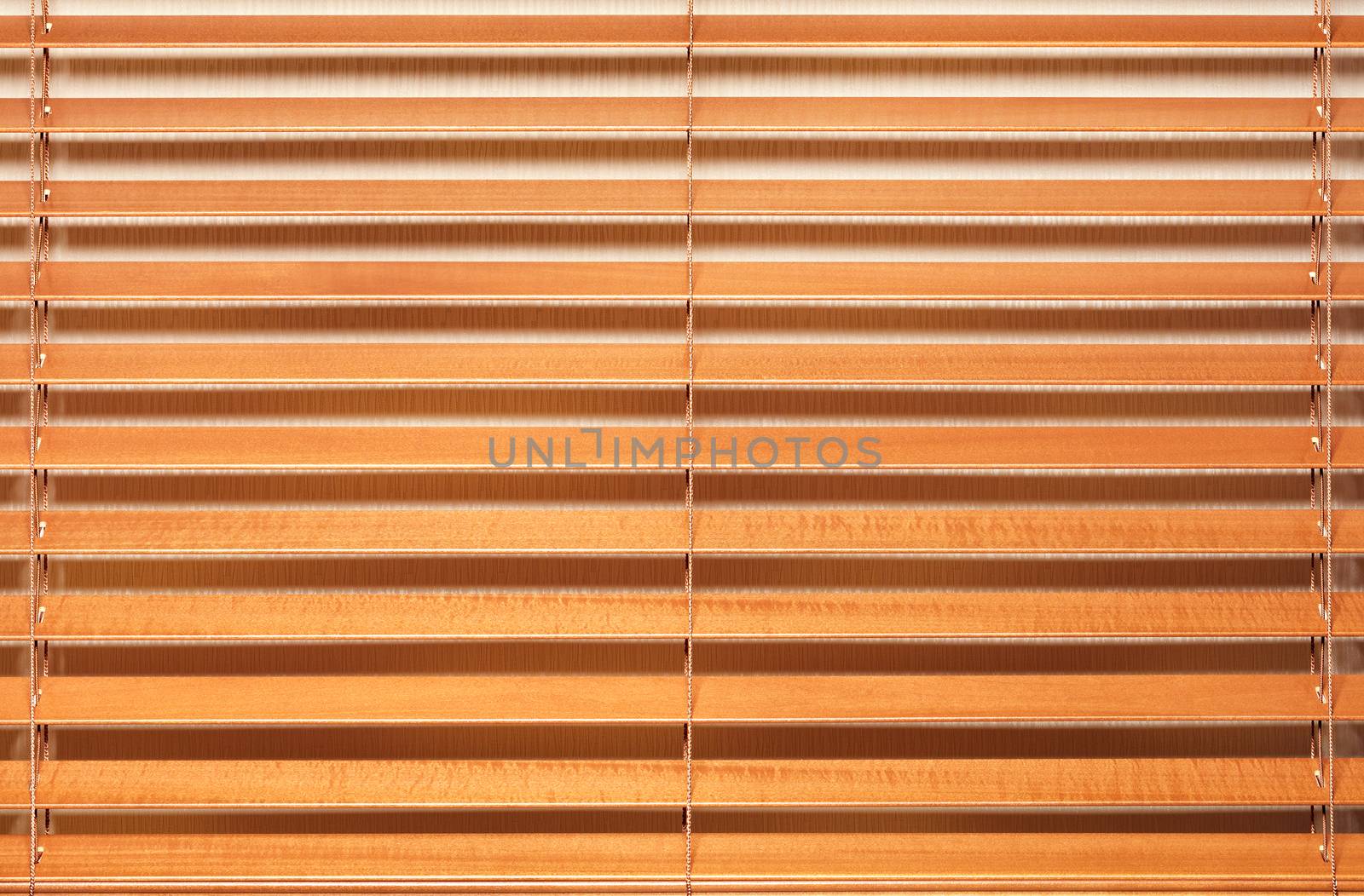 Background and texture of light brown, wooden blinds with wide slats in a horizontal line.