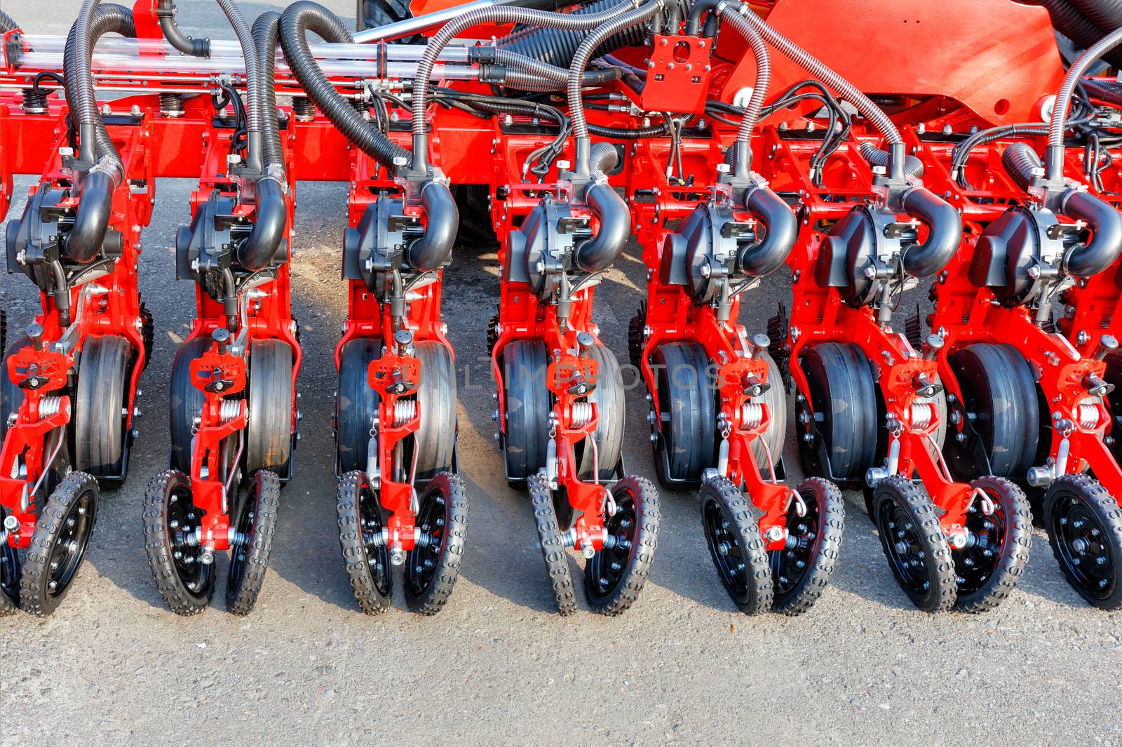 Red modern multi-row seeder, wheels, distribution pipes and working mechanisms of pneumatic agricultural seeder, copy space.