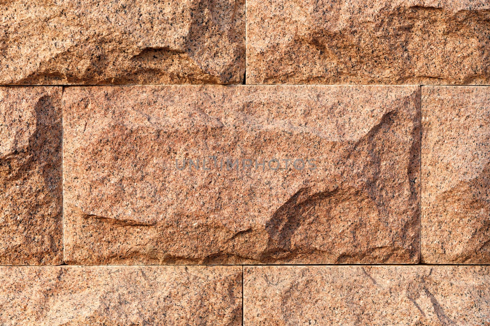 The texture of red granite and the background in the form of large processed blocks, stacked on top of each other in the light of warm sunlight, form a frame, copy space.