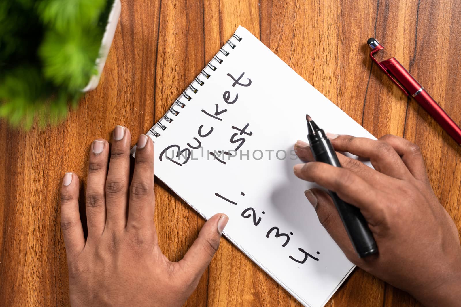 POV shot of hands writing or planning down Bucket list on note book for 2021 new year