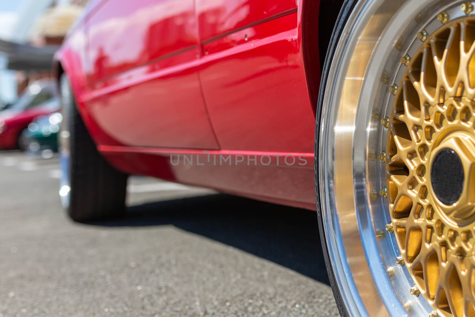 Automotive wheel. Beautiful golden wheel on a background of a sports red car.