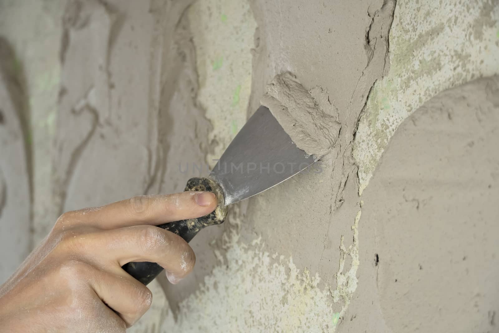 A worker plasters the wall with a spatula and applies a cement m by YevgeniySam