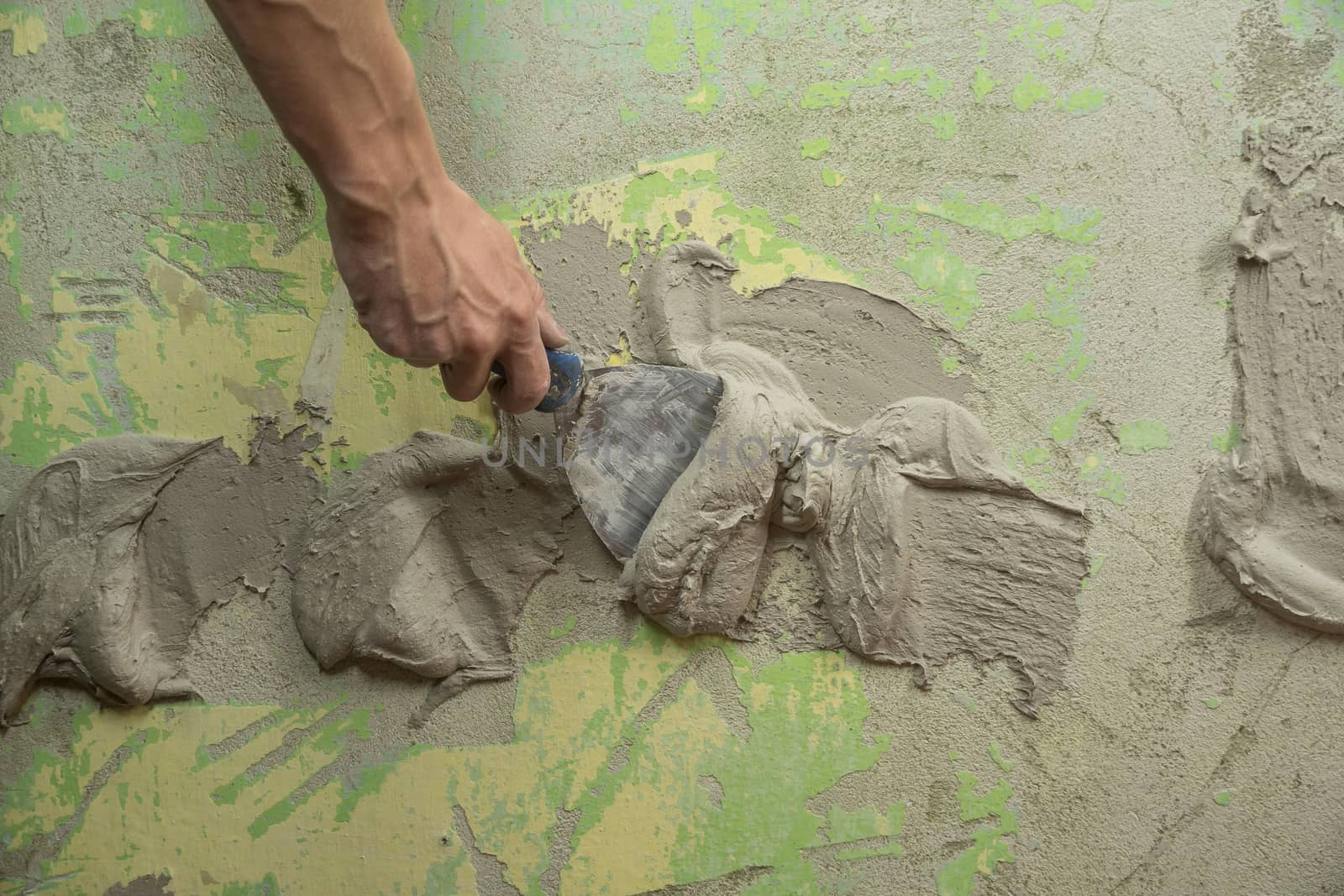 A worker plasters the wall with a spatula and applies a cement m by YevgeniySam