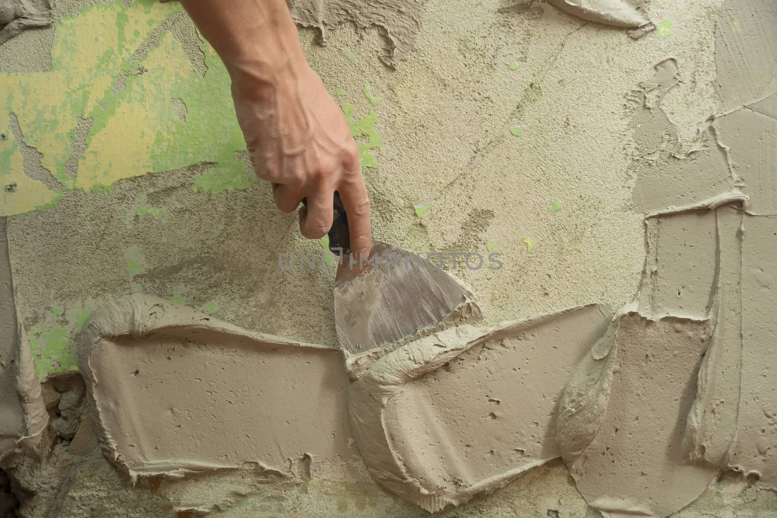 A worker plasters the wall with a spatula and applies a cement mix solution. The repairman lays the plaster on the drywall. Handyman repairs home. Laborer restore dwelling. Specialist covers up cracks