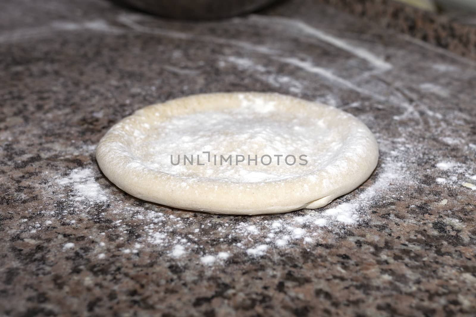 Pizza raw dough floured lies on granite table. Dough preparation for Italian pizza. Cooking food. Horizontal image