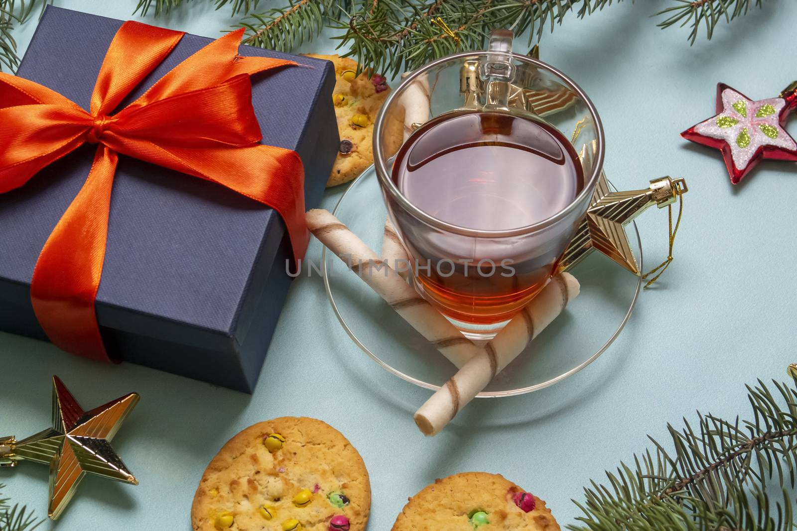 a Cup of warm tea is surrounded by Christmas toys, Christmas cookies and fir branches