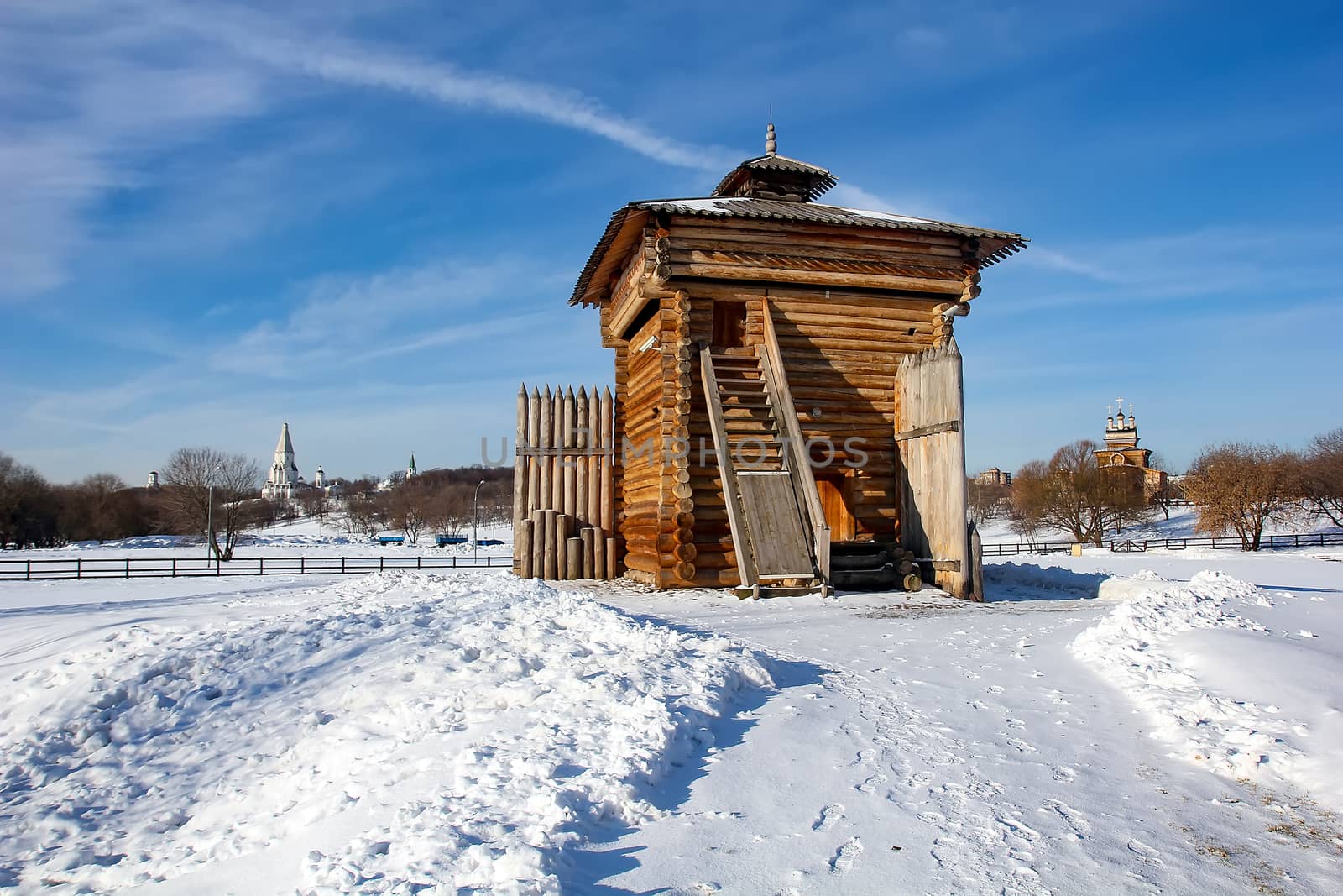 The Wooden Tower of the Bratsk fortress in Kolomenskoye. Russian wooden military structure in Moscow from Siberia. Winter landscape with a snowy road and a beautiful blue sky.