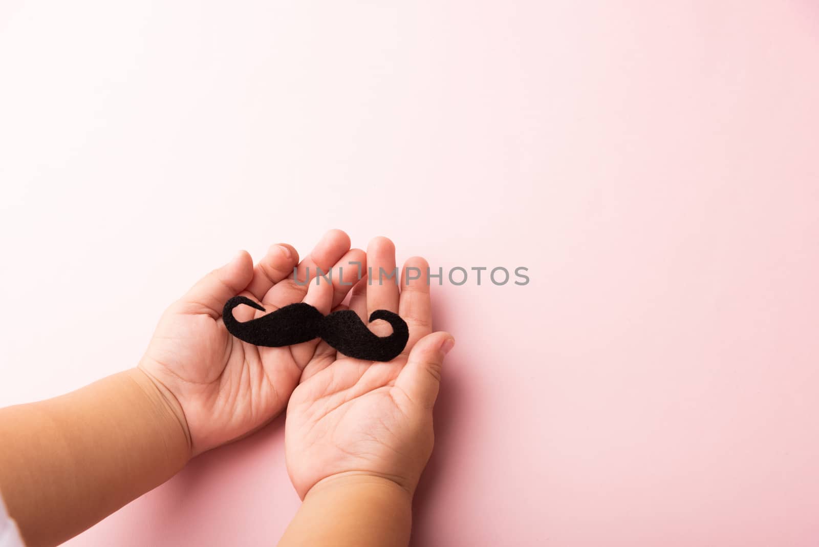 The kid uses hand holding black mustache, studio shot isolated on white background, Prostate cancer awareness month, Fathers day, minimal November moustache concept