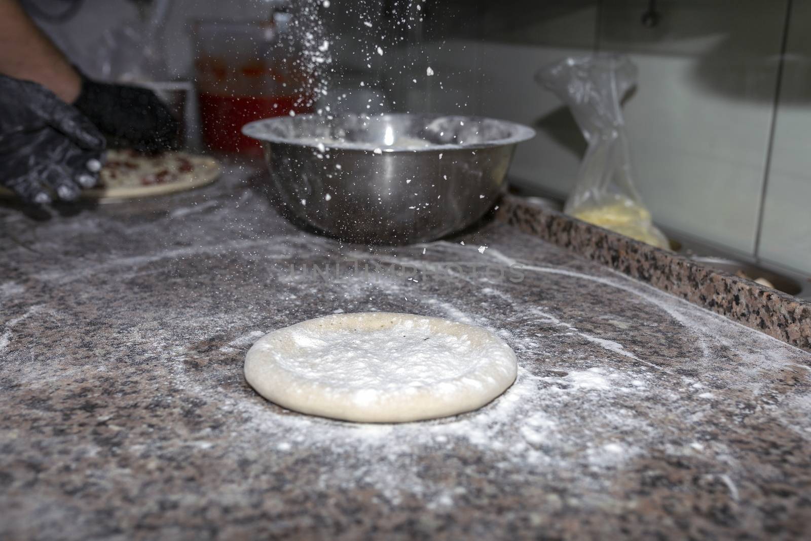 Pizza raw dough floured lies on granite table. Dough preparation for Italian pizza. Cooking food.