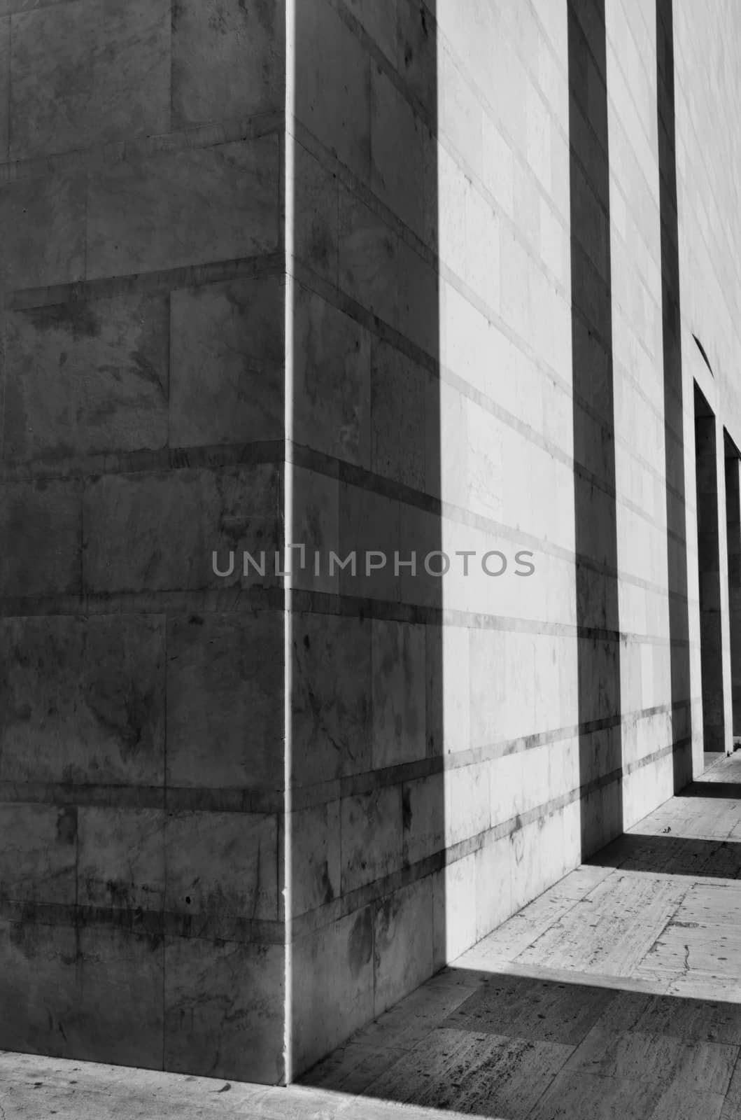 Shadows of a columns row cast on a building facade ,black and white photo ,geometic shape ,vertical composition ,wide angle lens ,