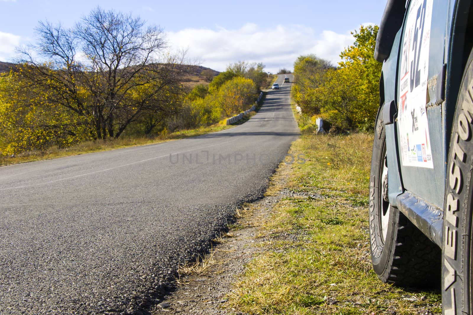 Tbilisi, Georgia - November 08, 2020: Suzuki car on the road, highway, autumn tree, plants and blue cloudy sky in Georgian country