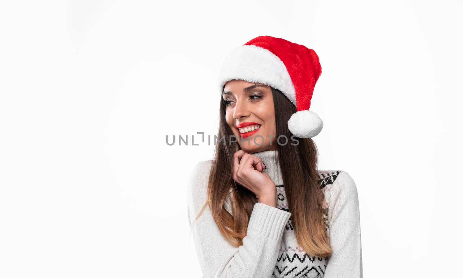 Close up portrait beautifiul caucasian woman in red Santa hat on white studio background. Christmas New Year holiday concept Cute girl hugs himself teeth smiling positive emotions with free copy space