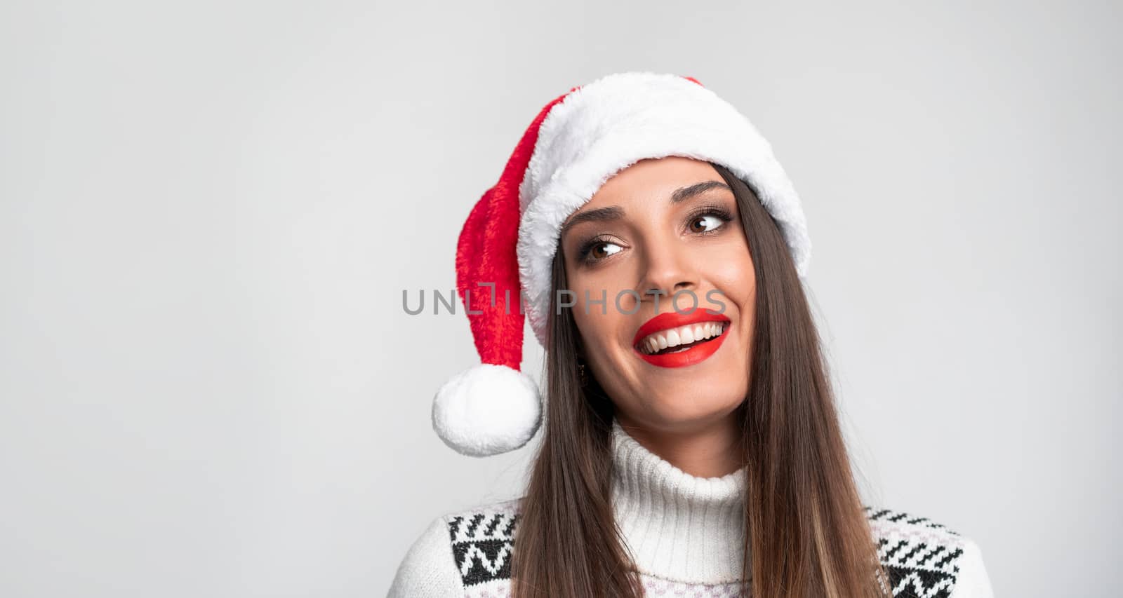 Close up portrait beautifiul caucasian woman in red Santa hat on white studio background. Christmas New Year holiday concept. Cute girl teeth smiling positive emotions with free copy space