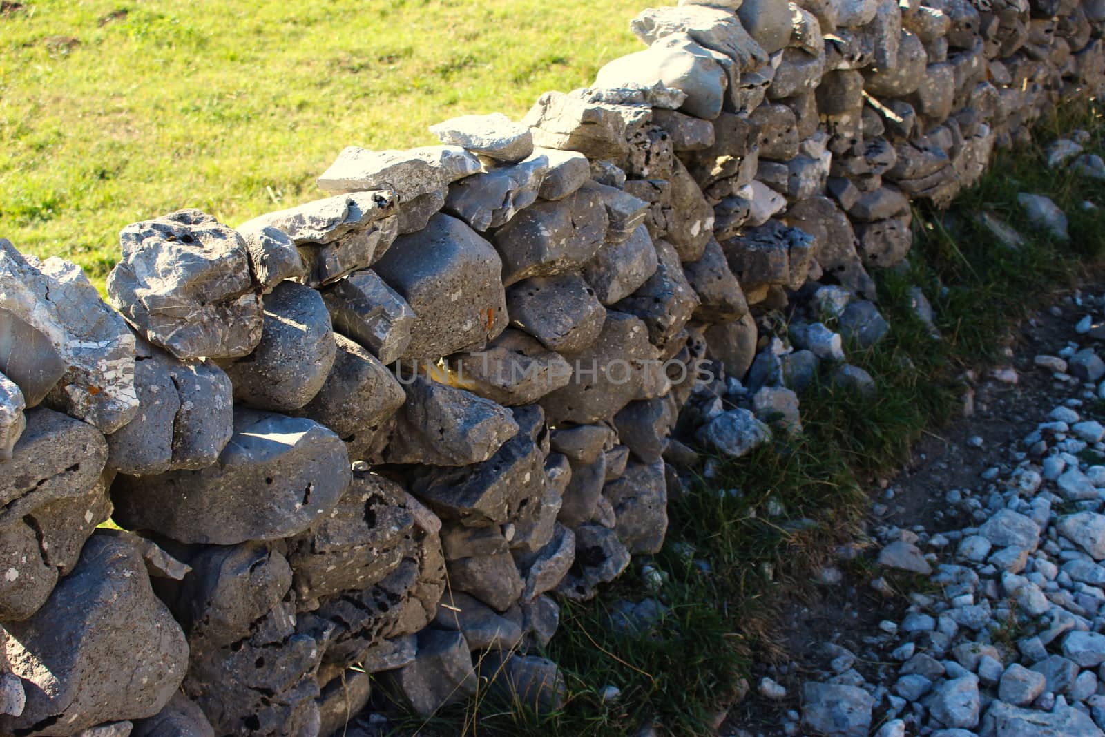 Large stones stacked in the wall to fence off the field from the road. Road to the old Bosnian village of Lukomir. Bjelasnica Mountain, Bosnia and Herzegovina.
