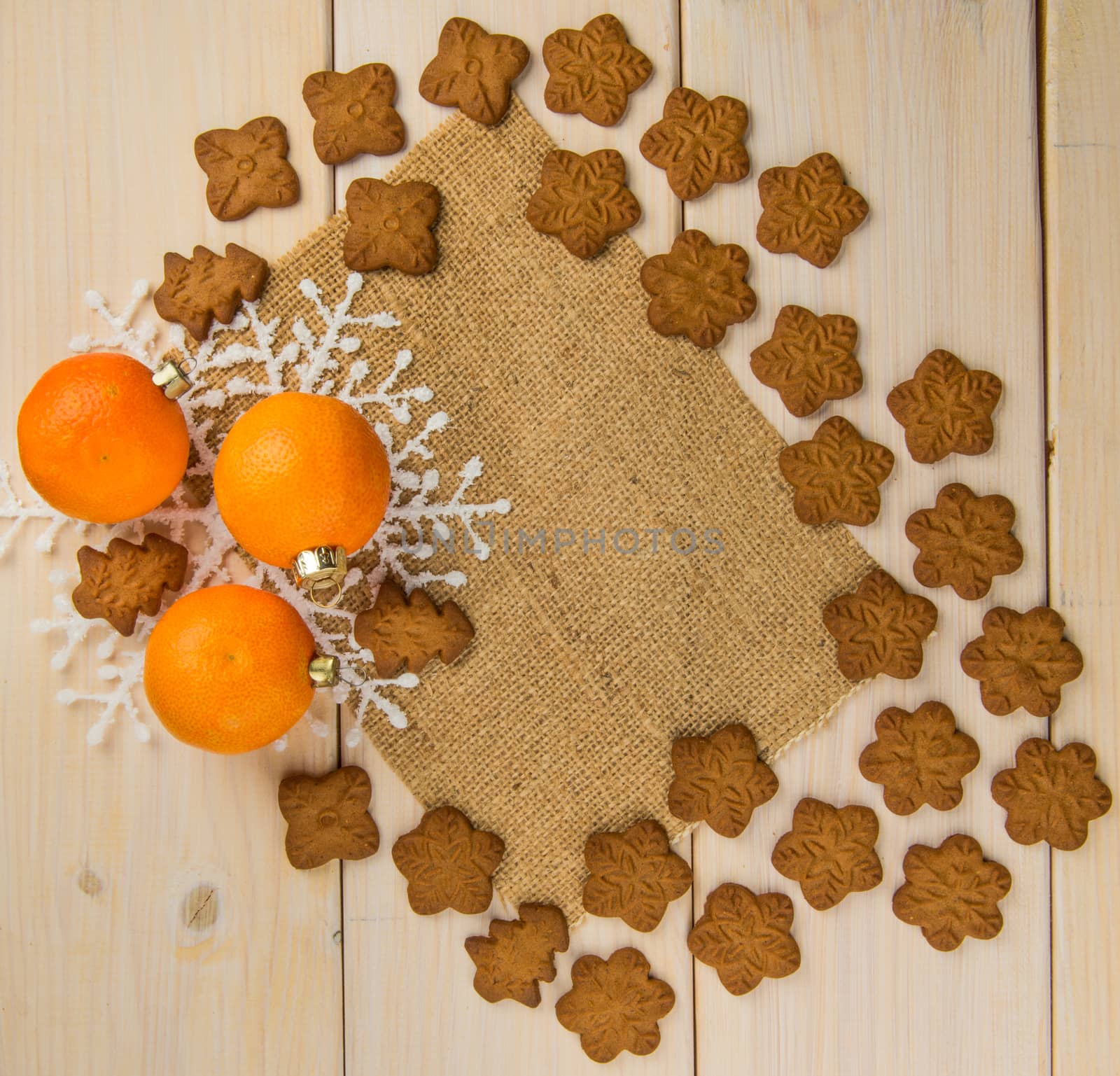 Christmas or New Year tangerines and gingerbread cookies with snowflakes framed on wooden background with brown sack background texture for text and your design.