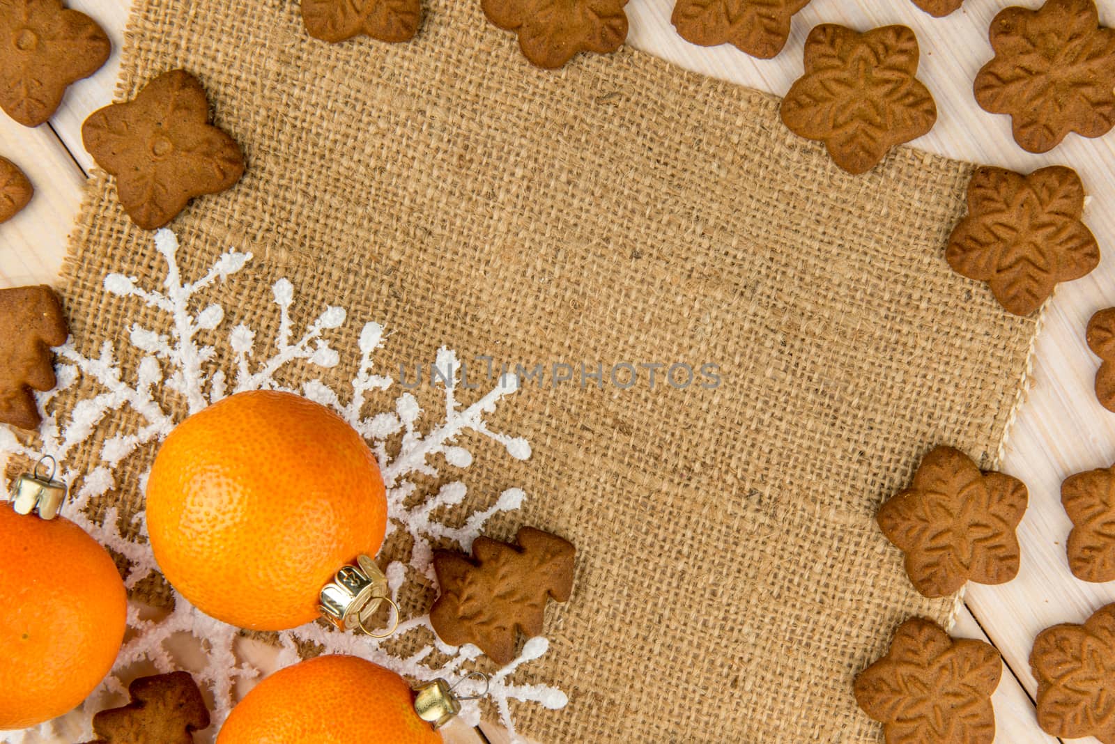 Christmas or New Year tangerines and gingerbread cookies with snowflakes framed on wooden background with brown sack background texture for text and your design.
