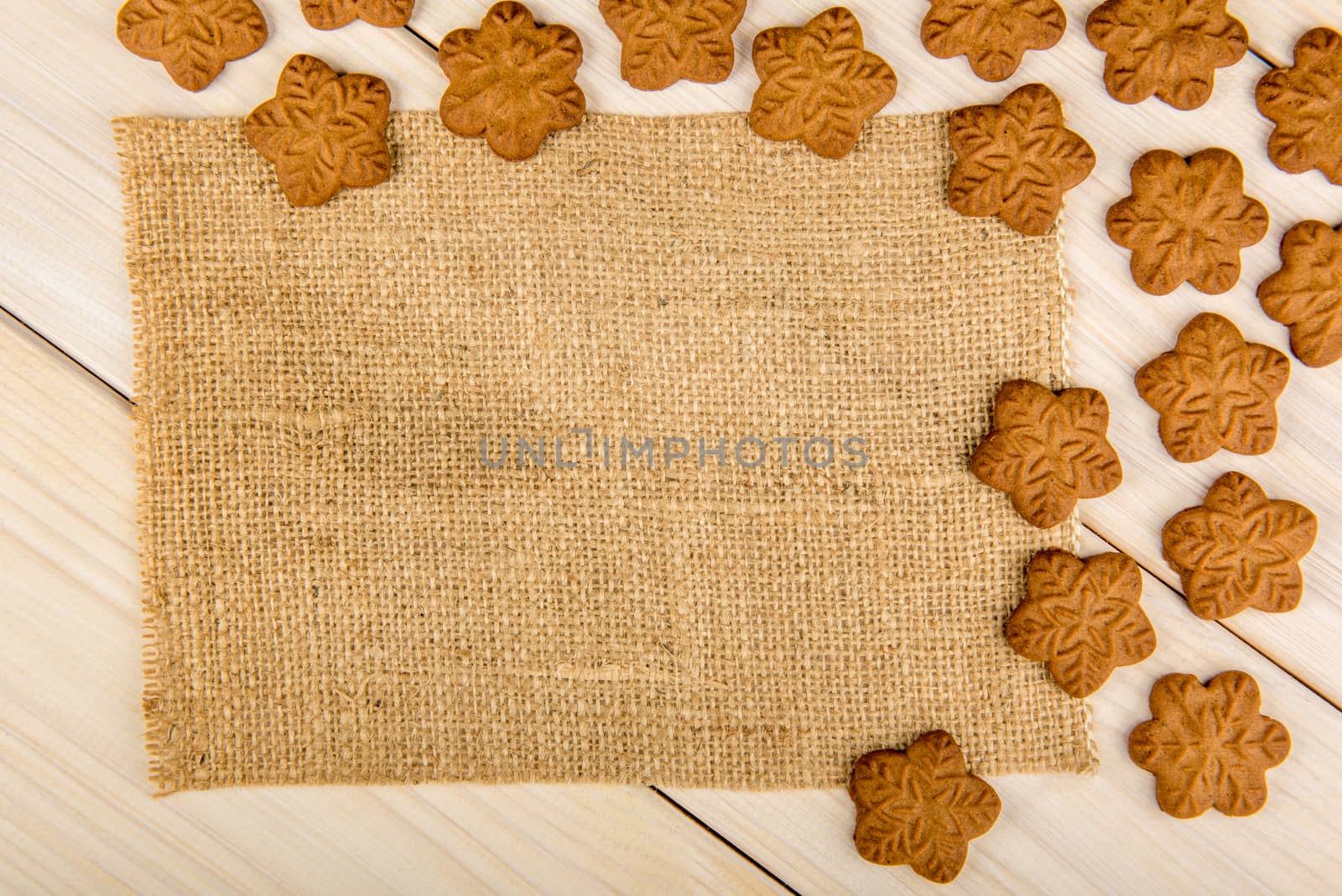 Christmas or New Year gingerbread cookies with snowflakes framed on wooden background with brown sack background texture for text and your design.