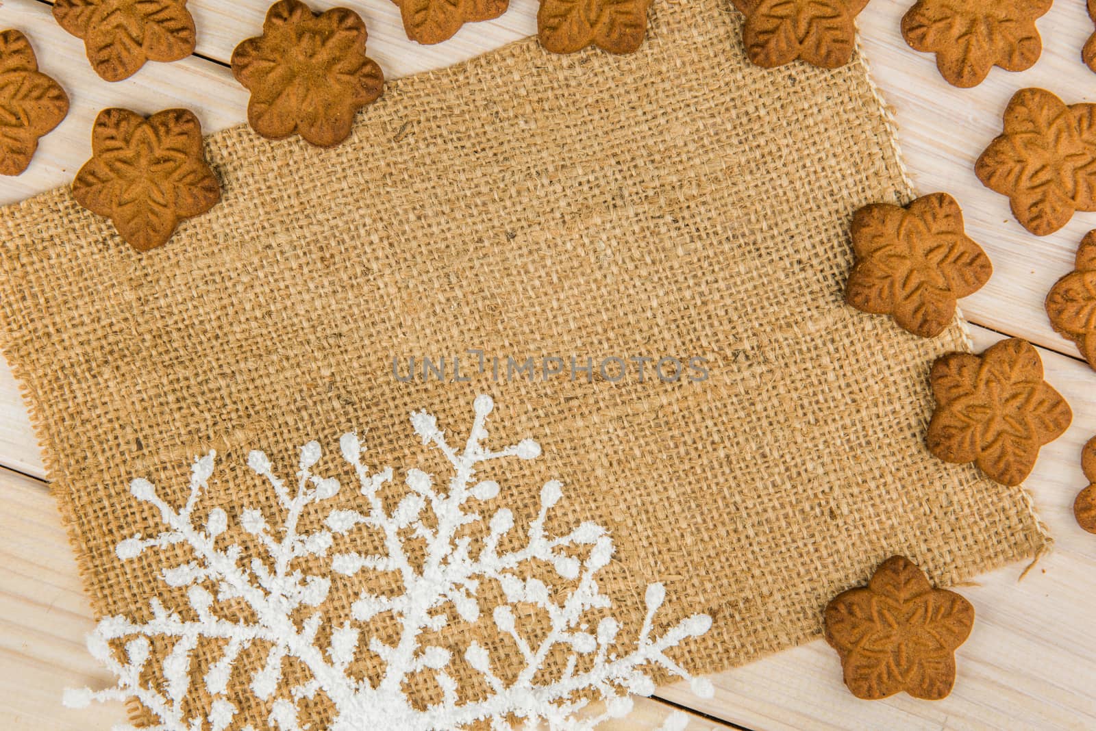 Christmas or New Year gingerbread cookies with snowflakes framed on wooden background with brown sack background texture for text and your design.