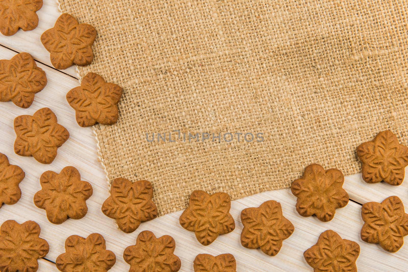 Christmas or New Year gingerbread cookies with snowflakes framed on wooden background with brown sack background texture for text and your design.