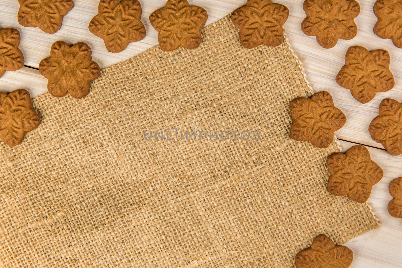 Christmas or New Year gingerbread cookies with snowflakes framed on wooden background with brown sack background texture for text and your design.