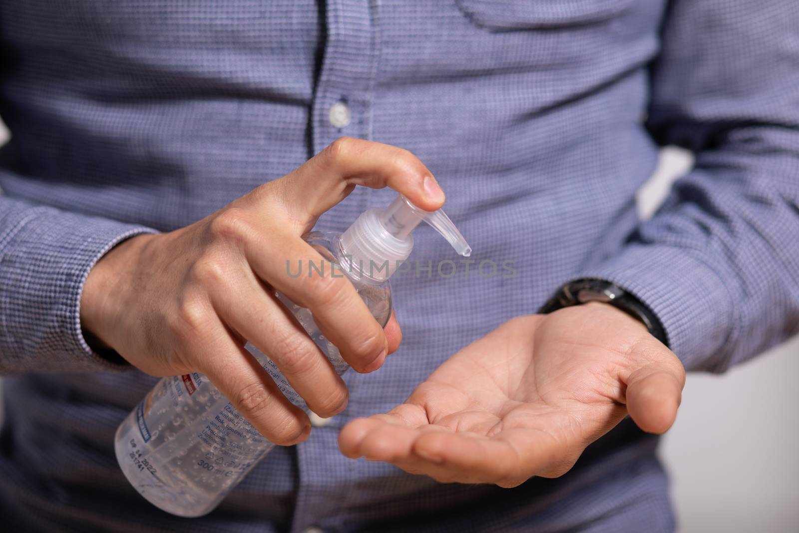 Man applying disinfectant alcohol gel on hands by adamr