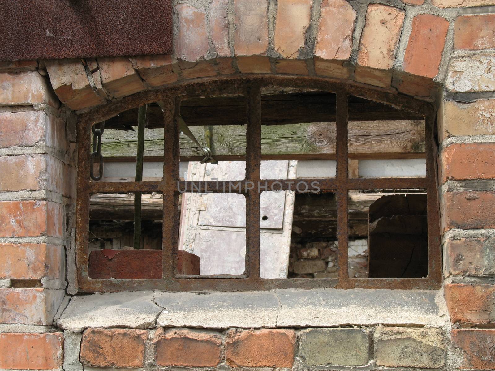 A rusty barred window in an old brick wall.