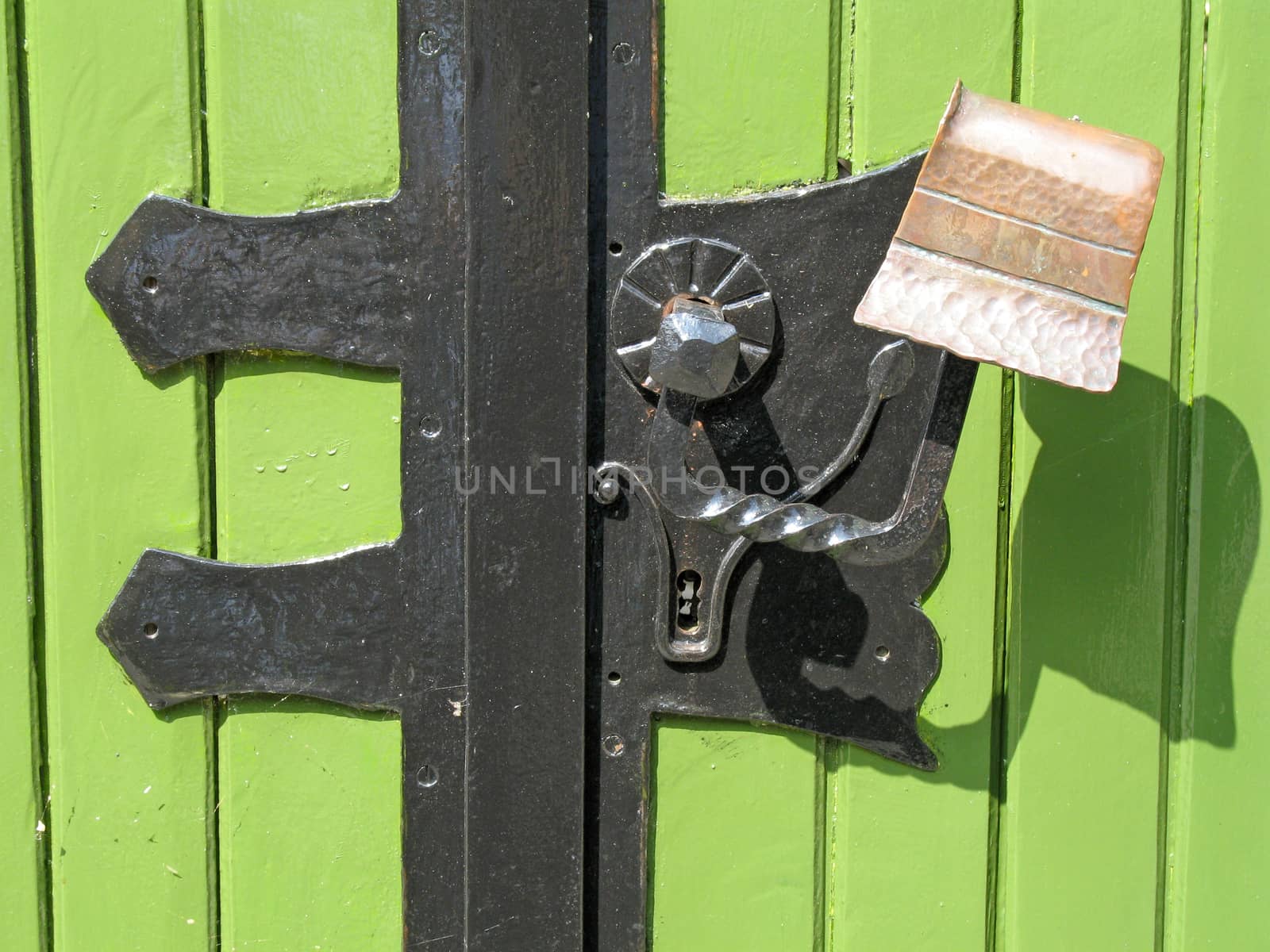 Green painted door with handle made of wrought iron and copper.