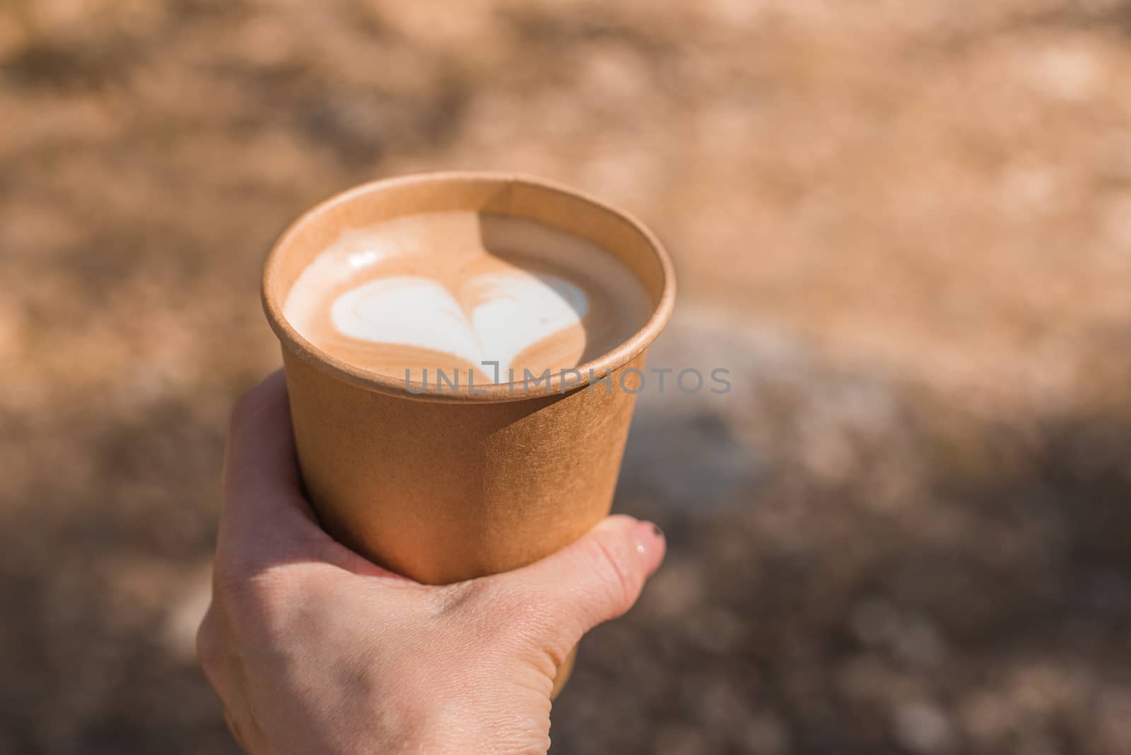 hand holding paper cup of coffee on nature background by infinityyy
