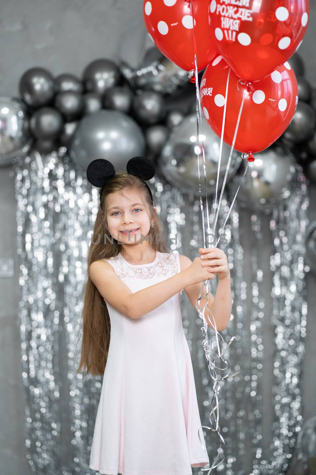 Little girl with red balloons celebrates her birthday.