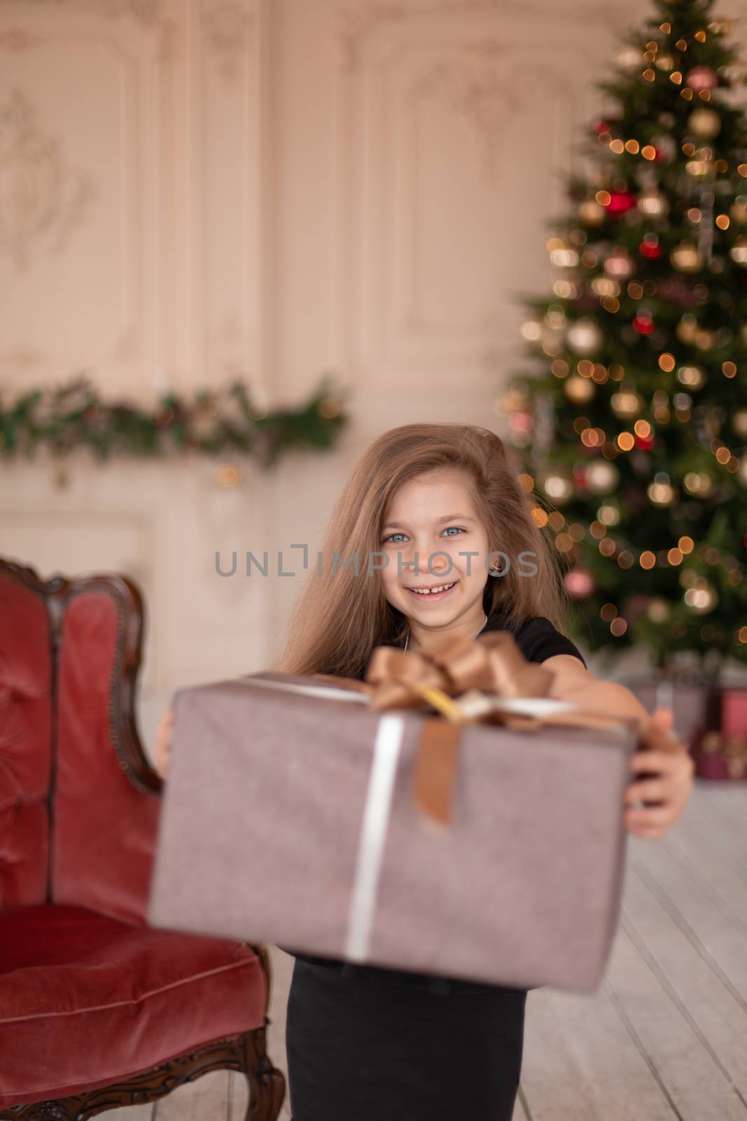 A little girl opens a Christmas present from Santa. Christmas tale. Happy childhood.