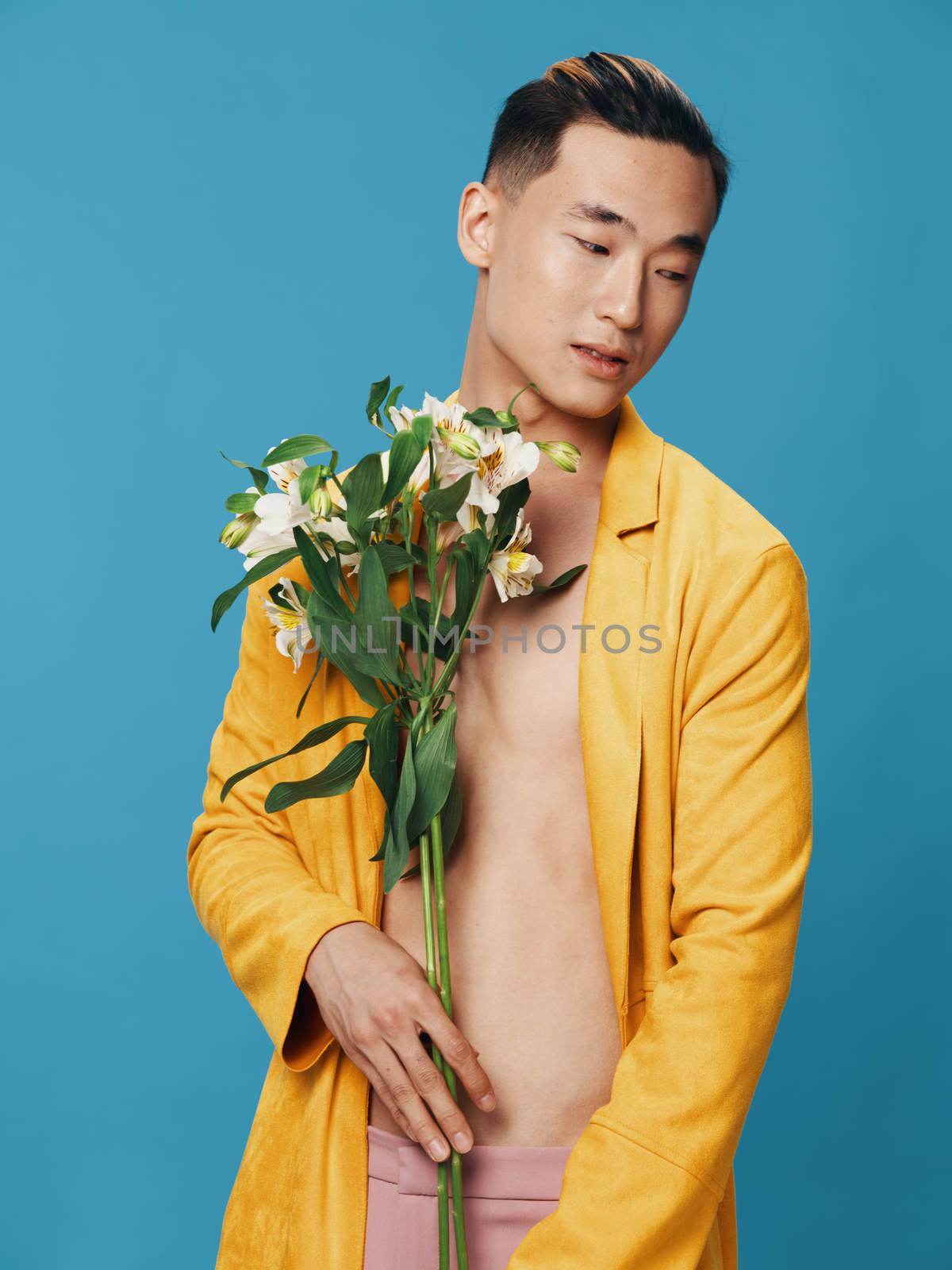 A man with white flowers in his hands looks to the side against a blue background. High quality photo