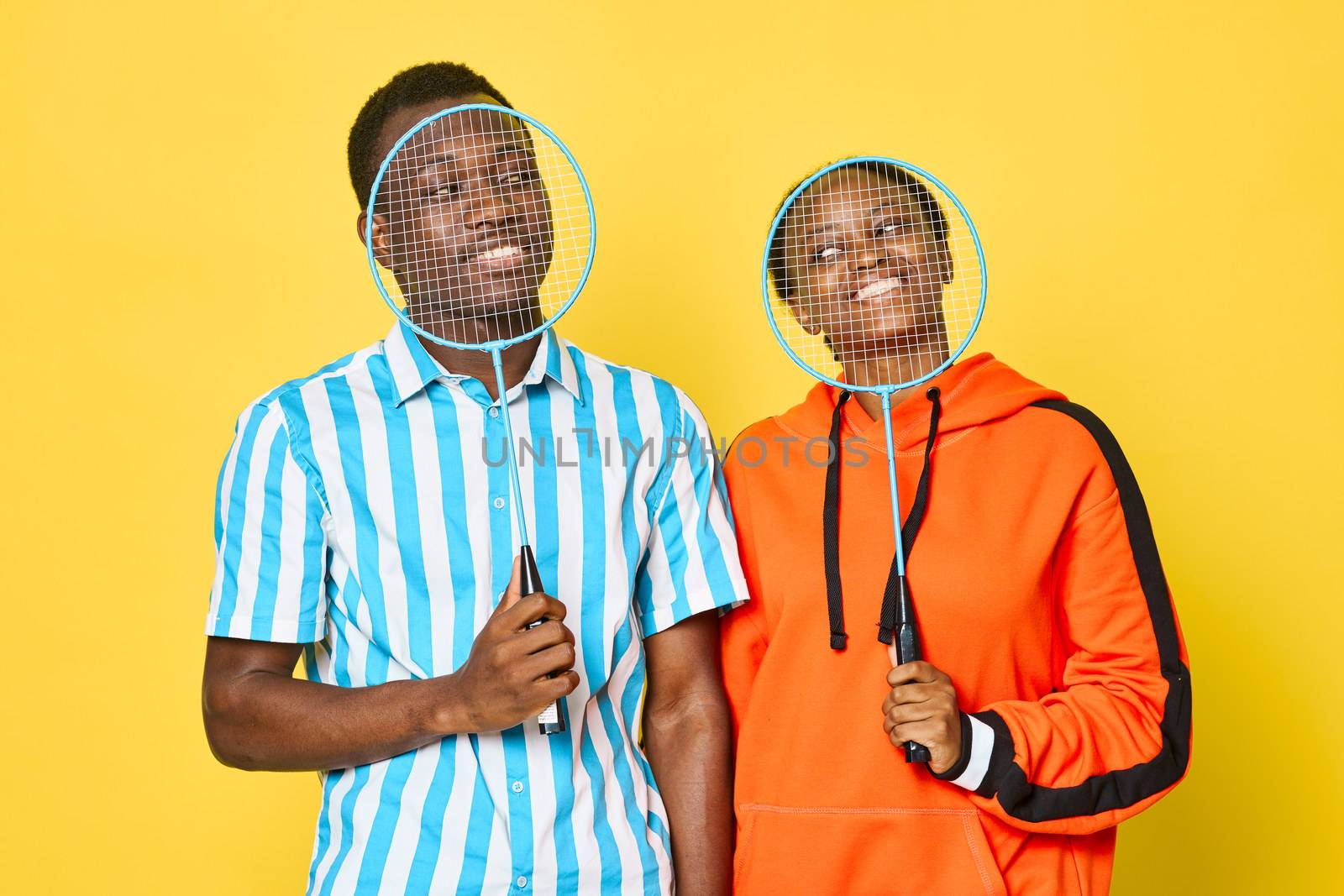 sports guy and woman of african appearance with badminton rackets in hands