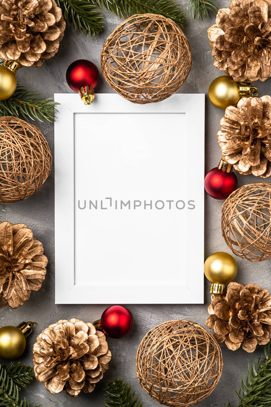 Christmas composition with empty picture frame. Golden ornament, pine cones and fir needles decorations. Mock up greetings card template