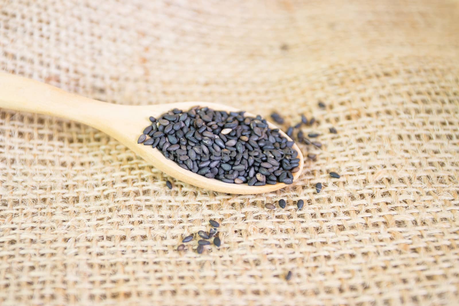 Black sesame seeds in wooden spoon pile 