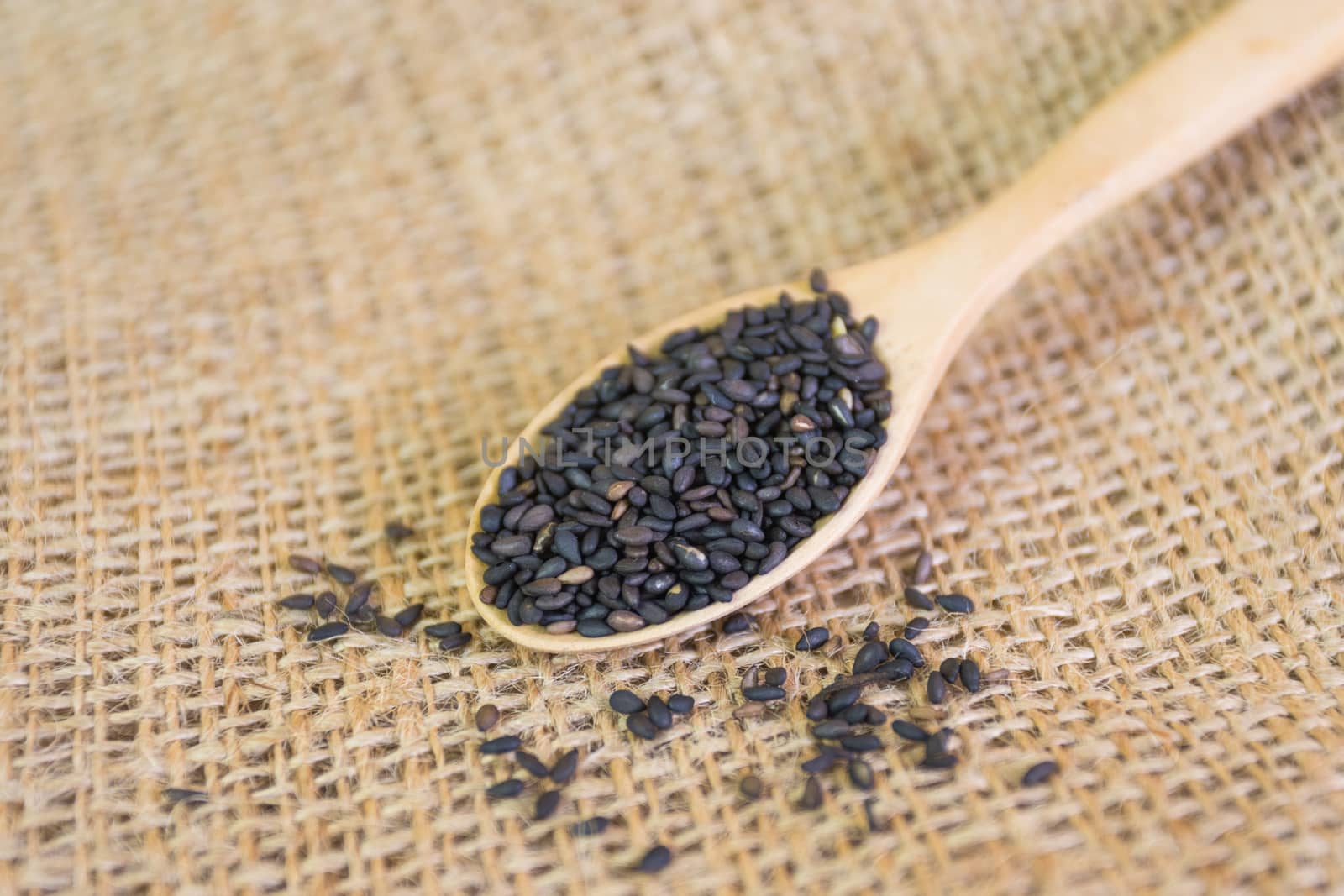 Black sesame seeds in wooden spoon pile  