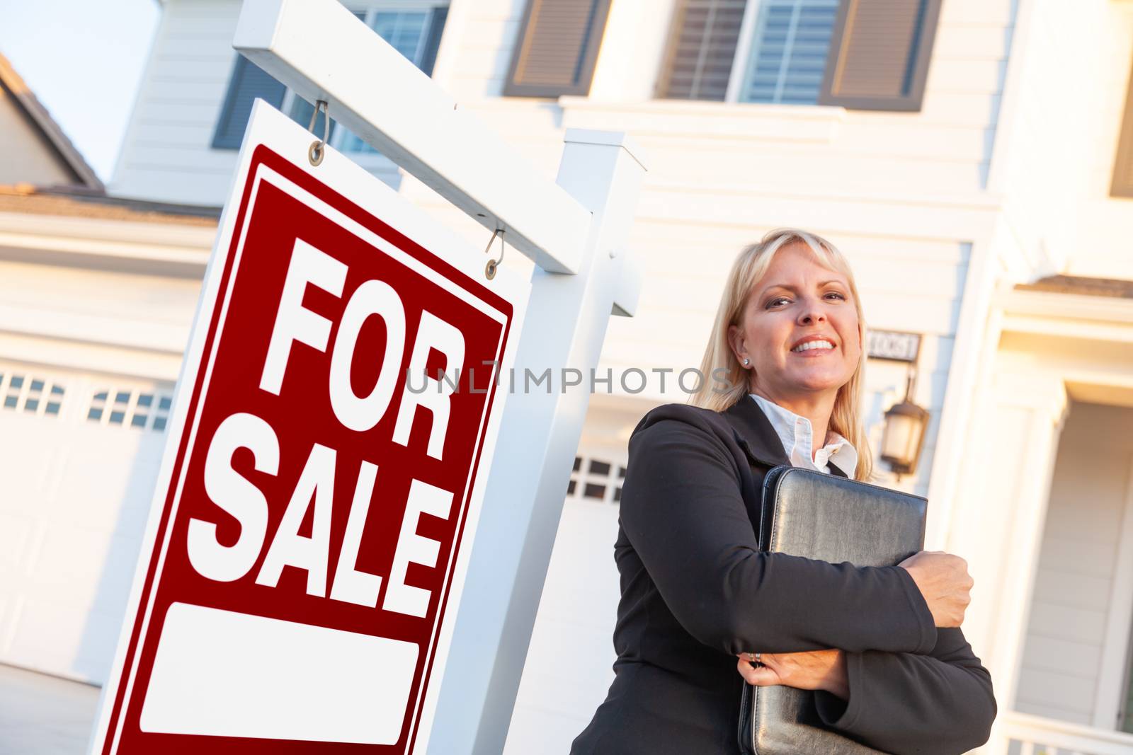 Female Real Estate Agent in Front of For Sale Sign and Beautiful House.