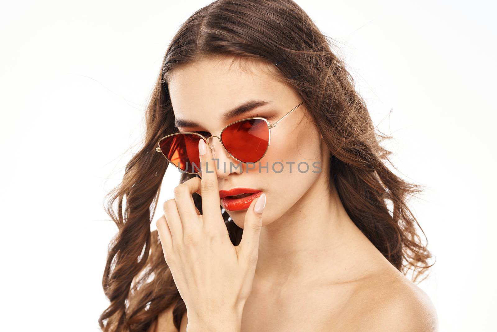 Portrait of brunette woman in sunglasses naked shoulders light background. High quality photo