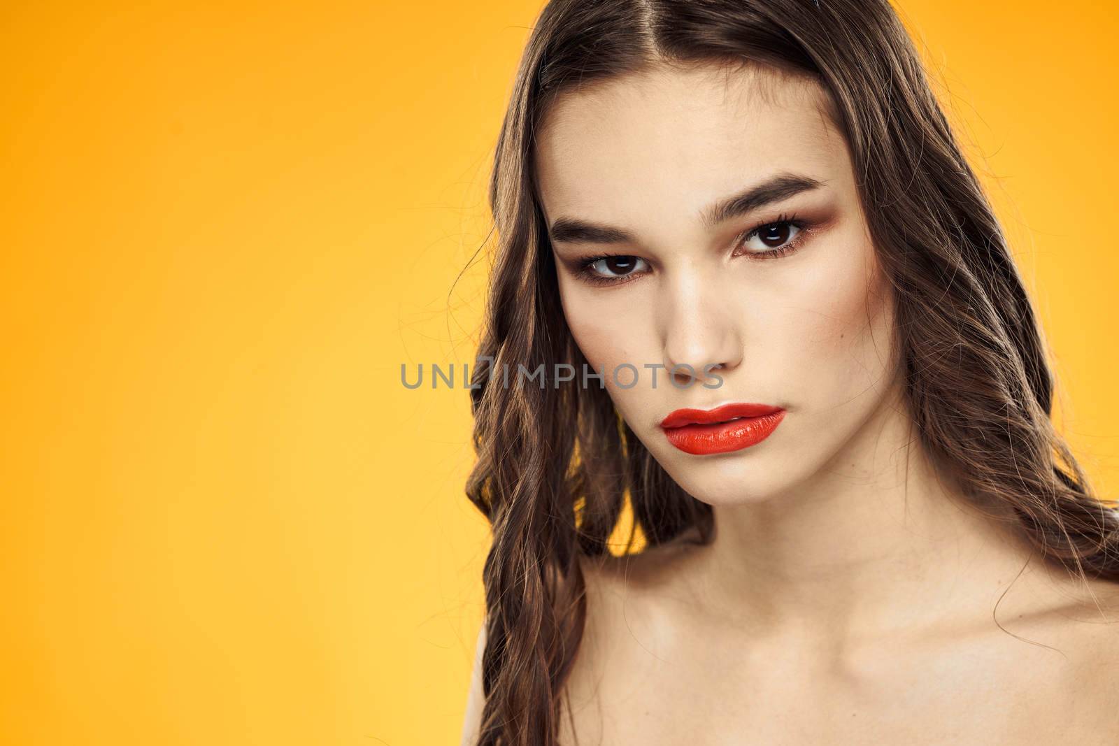 Beautiful brunette naked shoulders bright makeup red lips hairstyle close-up yellow background by SHOTPRIME